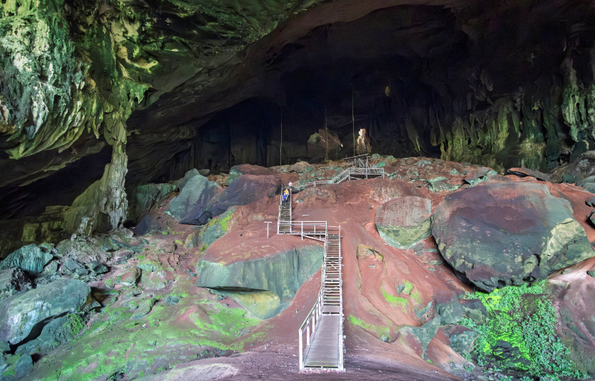 Tourists walk down a staircase at the Great Cave at Niah National Park